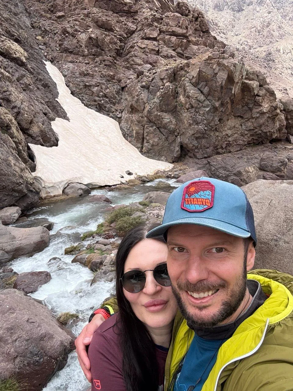 Two travellers beside a snowmelt river in the High Atlas mountains