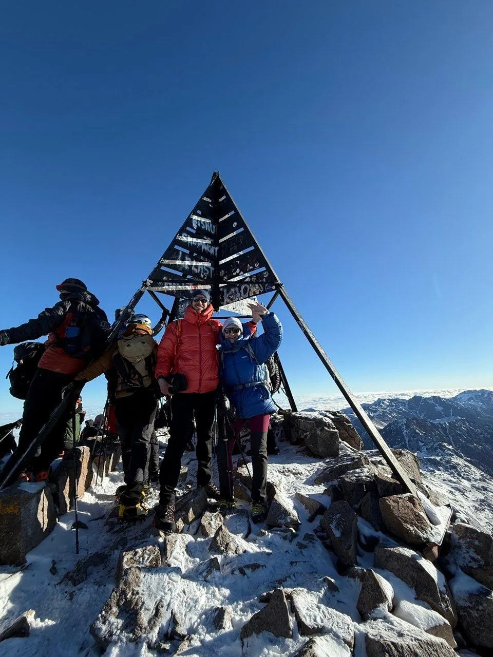 Trekkers at the iconic Mount Toubkal summit marker, above the clouds at 4,167 m